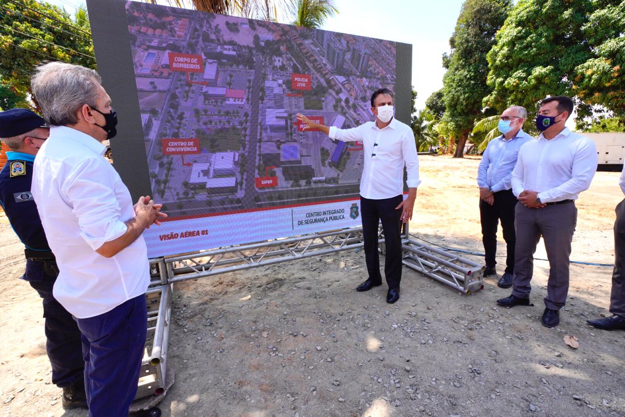 Governador em pé explicando maquete eletrônica exibida em telão